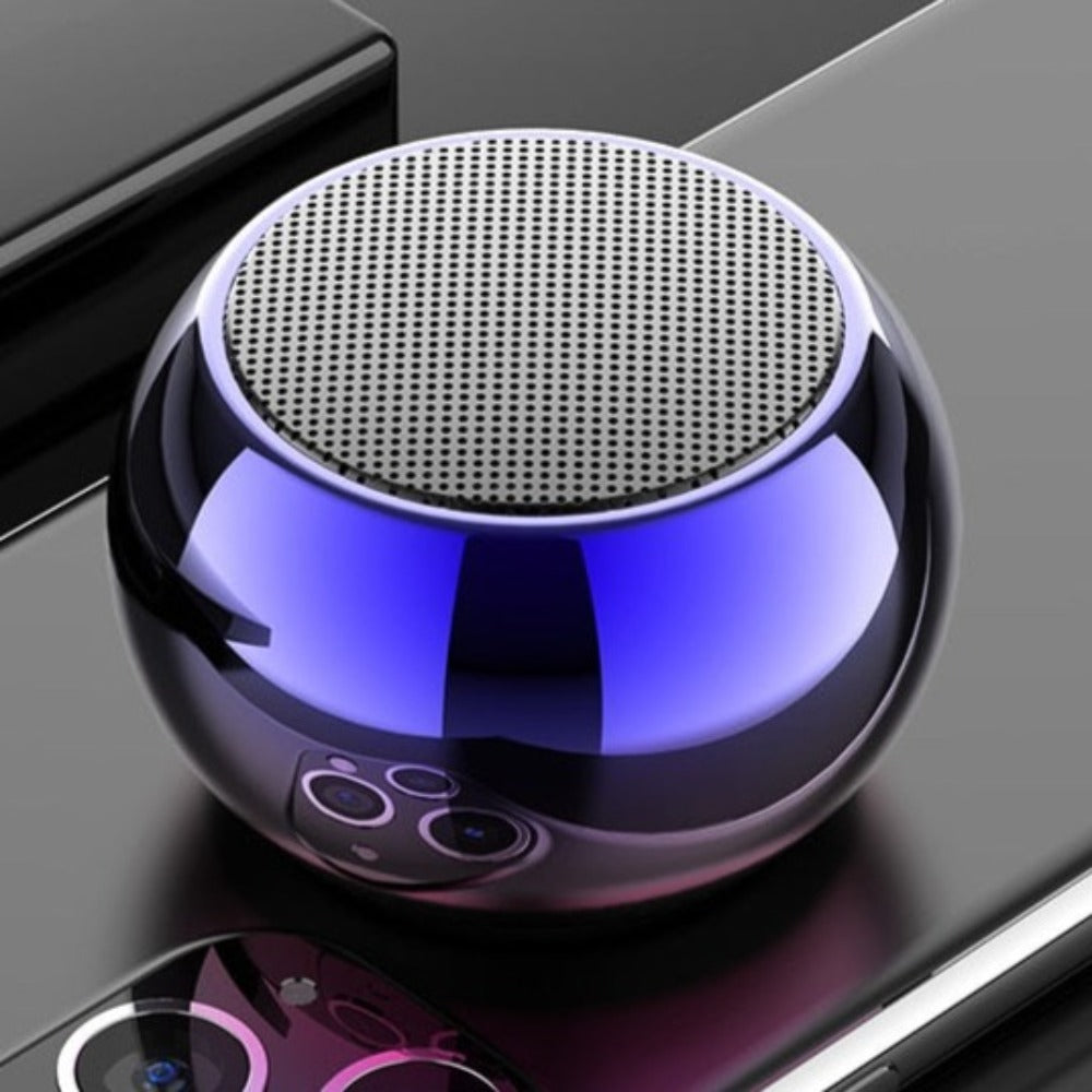 Round electronic device with blue and black design on a reflective surface. Dragon Mini Speaker - Bluetooth 5.0 Wireless Connectivity | Smart Glow Connect