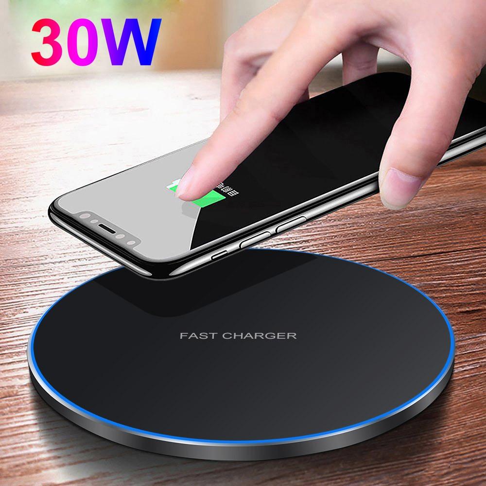 Hand placing a smartphone on a wireless charger with '30W' text, on a wooden surface. Dragon W9 30W Fast Wireless Charging Pad - Ultra Thin Design | Smart Glow Connect